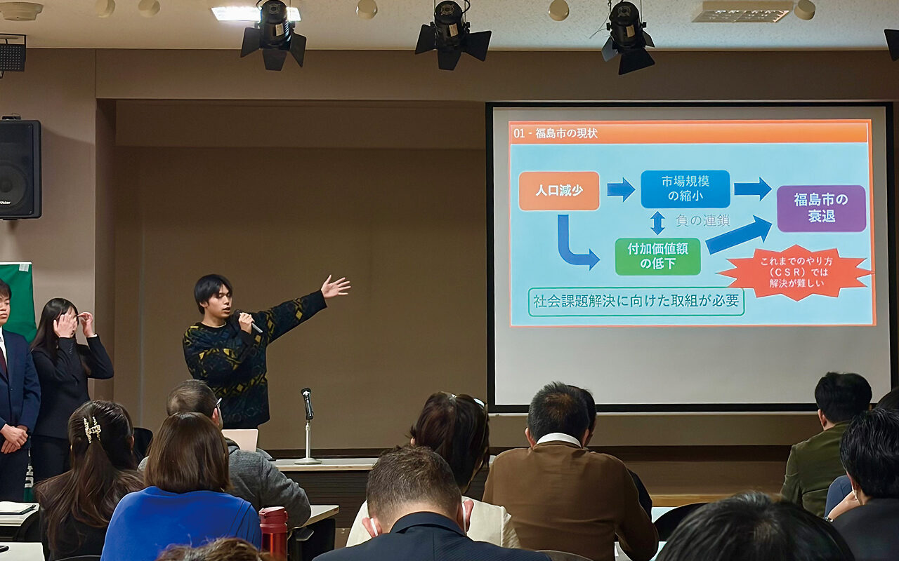 スクリーンの図を指しながら産学連携の成果を発表する登壇者